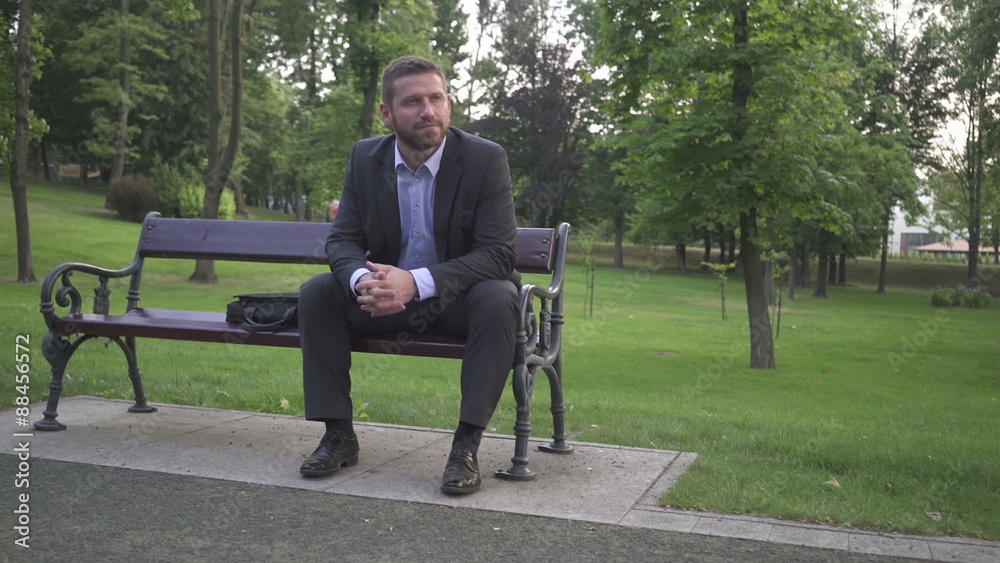 Businessman sitting and looking round, sitting on wood bench.
Businessman sitting and looking round, sitting on wood bench.