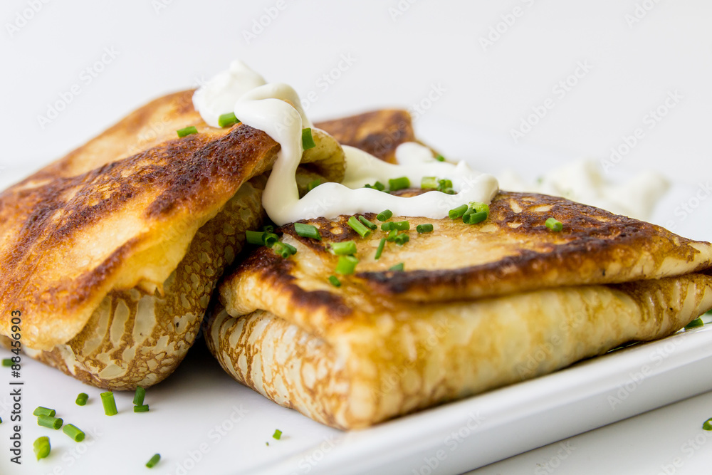 Two pancakes stuffed with meat with sour cream, isolated on white