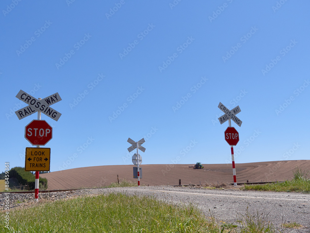 Obraz premium railway crossing signs with tractor in background. New Zealand. 