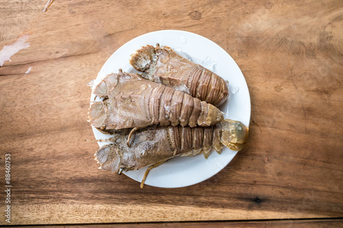 Fresh lobster in a white plate with ice on a wooden desk
