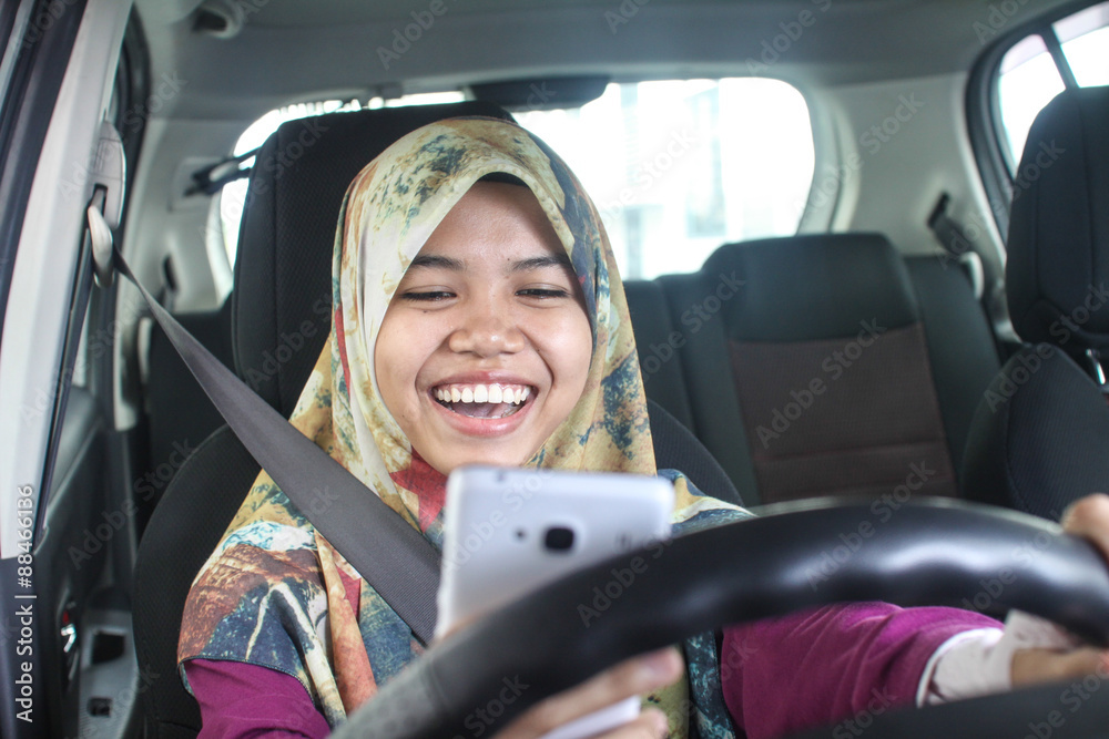 muslim woman holding handphone while driving muslim woman holding handphone while driving