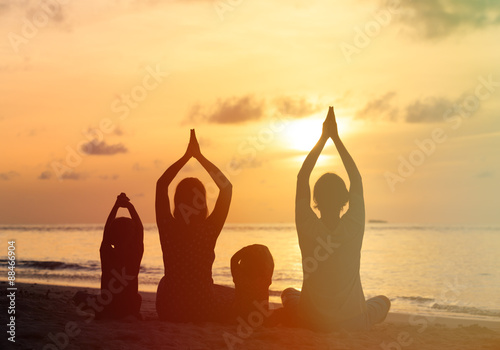 family silhouettes doing yoga at sunset