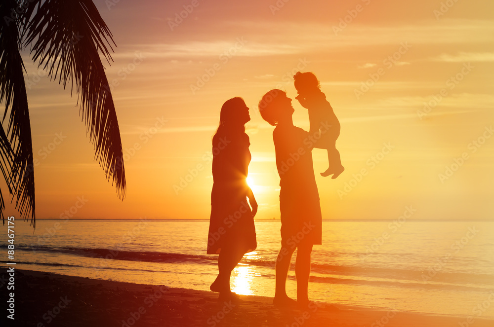 romantic couple with little child at sunset beach