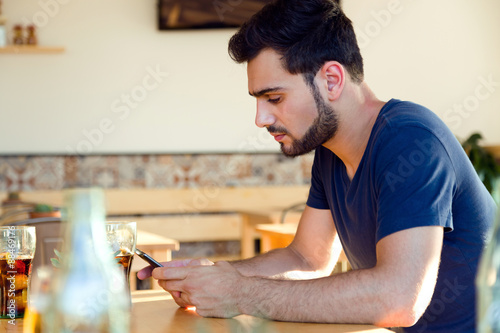 Modern young man with mobile phone in cafe.
