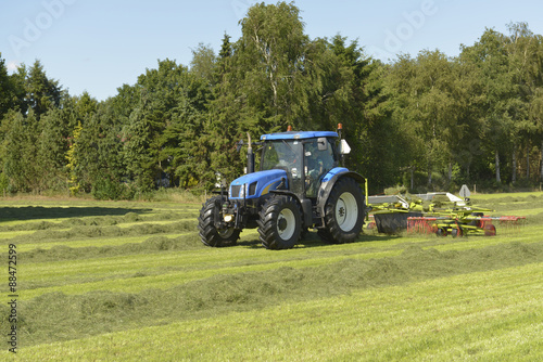 Agriculture  the kidding of shaken grass with blue tractor with