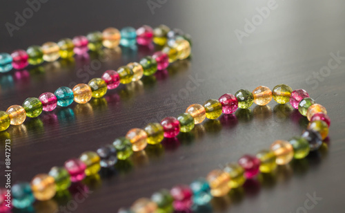 Necklace from glass beads of different colors on a dark surface close up