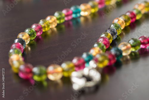 Necklace from glass beads of different colors on a dark surface close up