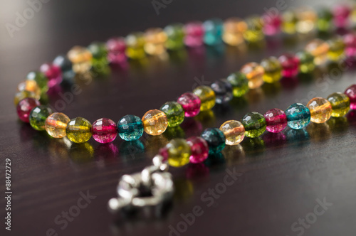 Necklace from glass beads of different colors on a dark surface close up