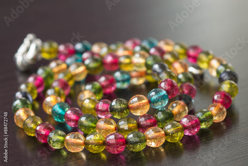 Necklace from glass beads of different colors on a dark surface close up