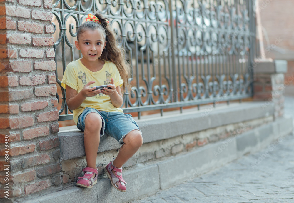 girl is sitting outdoor and playing on the phone girl is sitting outdoor and playing on the phone