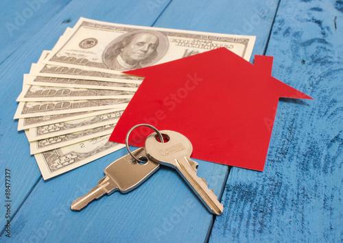 Many dollar banknotes, key and a house model. Concept of buying a house.