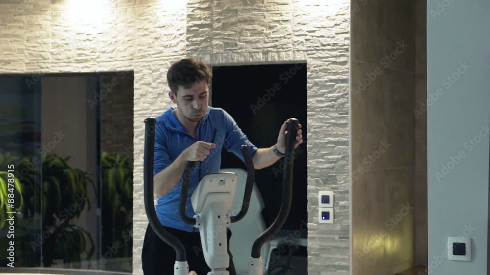 Man exercising on elliptical machine in gym and taking break, slow motion shot at 100fps
Man exercising on elliptical machine in gym and taking break, slow motion shot at 100fps