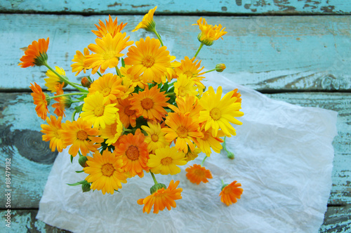 Yellow summer flowers of a calendula on a wooden surface. Summer background with a bouquet from a marigold. Calendula flowers.