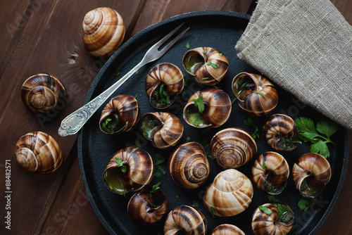 Baked snails with garlic butter and chopped parsley, close-up