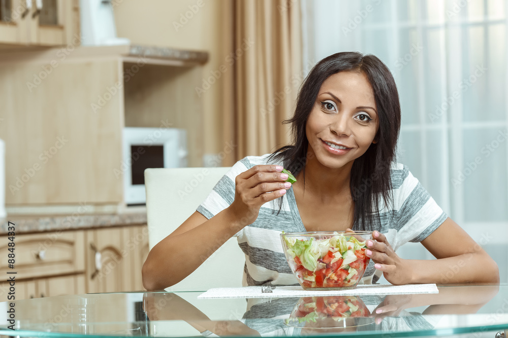 Beautiful woman eating fresh salad in modern kitchen