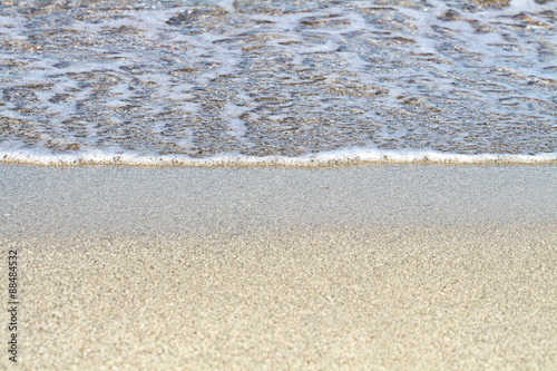Sand on the beach. Summer waves on the sandy beach. Sea water foam. Fine yellow sand.