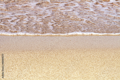 Sand on the beach. Summer waves on the sandy beach. Sea water foam. Fine yellow sand.