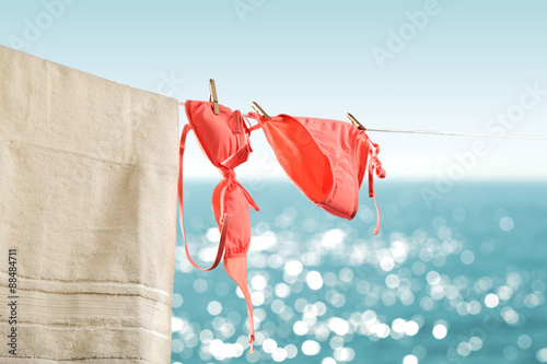 Foto Bikini and swimsuit hanging on a string with clothespins blurred bokeh sea and sky background on a hot sunny summer day