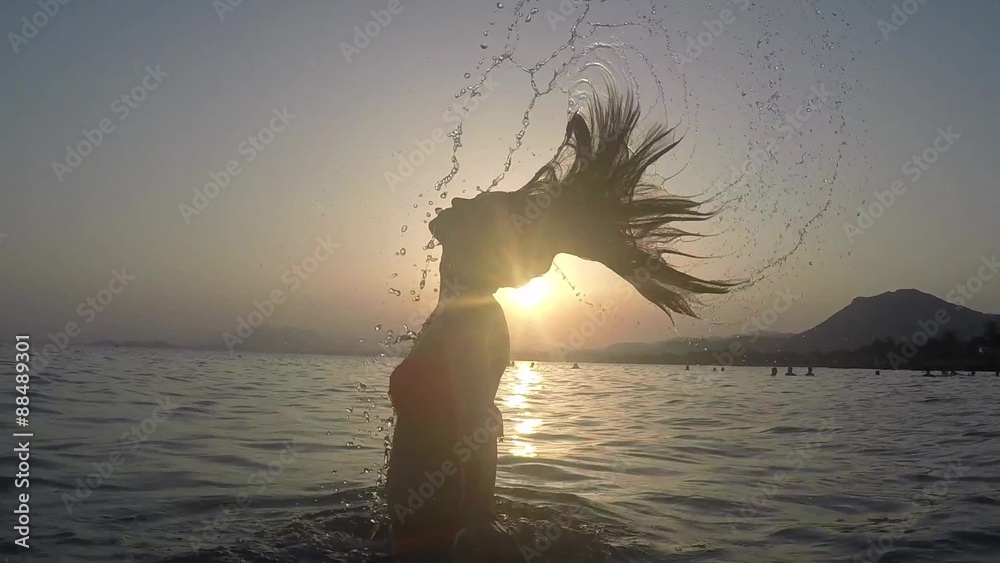 CHICA SALIENDO DEL MAR SALTANDO Y SALPICANDO CON SU PELO: grabado a cámara lenta a 120fps camara en mano