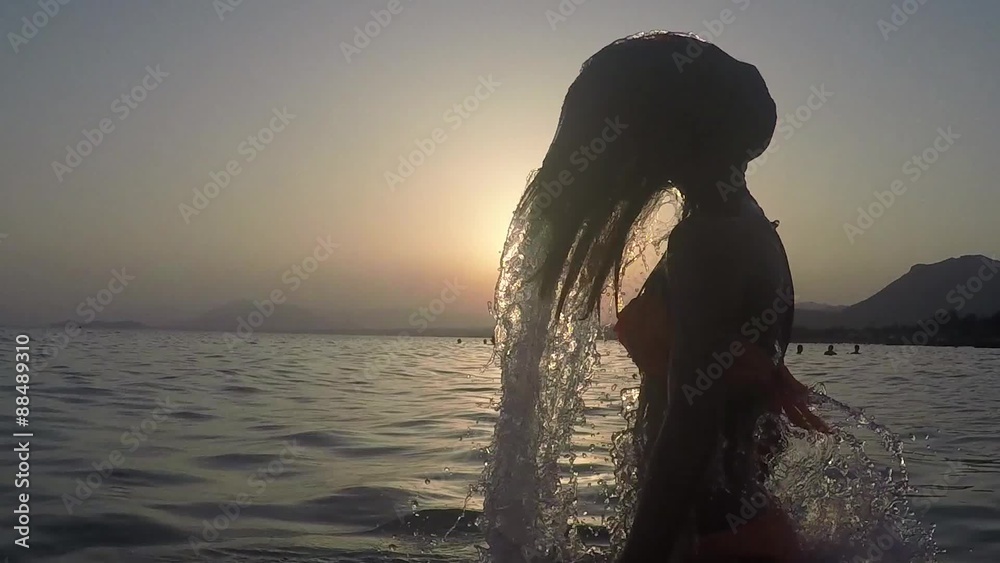 CHICA SALIENDO DEL MAR SALTANDO Y SALPICANDO CON SU PELO: grabado a cámara lenta a 120fps camara en mano