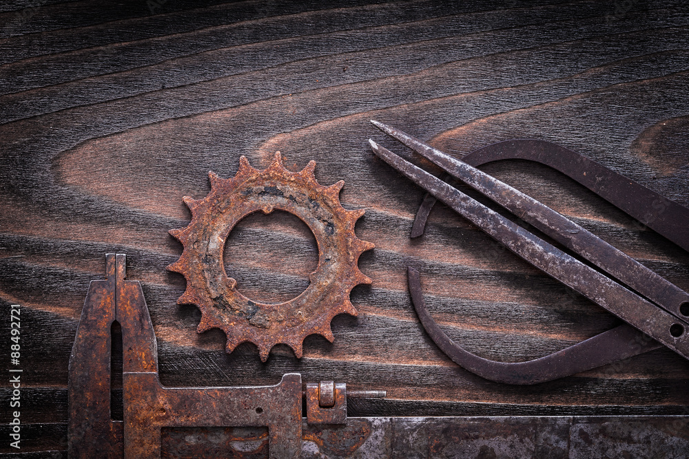 Rusted antique measuring calipers with gear wheel on vintage dar Rusted antique measuring calipers with gear wheel on vintage dar