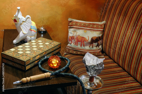 Restaurant interior still life, with a hookah, a chess-board, an elephant figurine