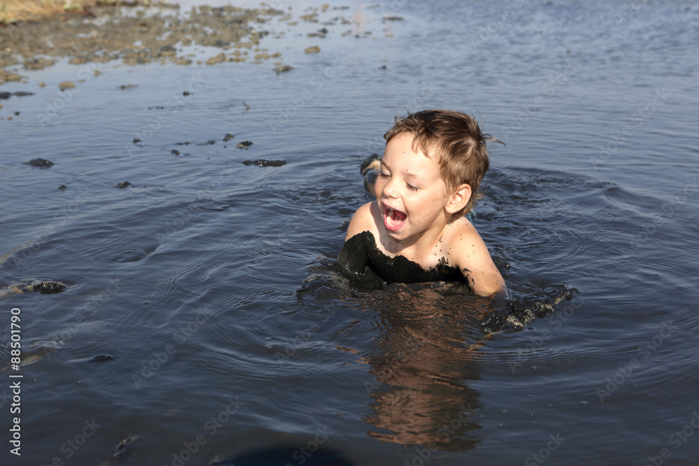 Fototapeta premium Boy lying in the black mud
