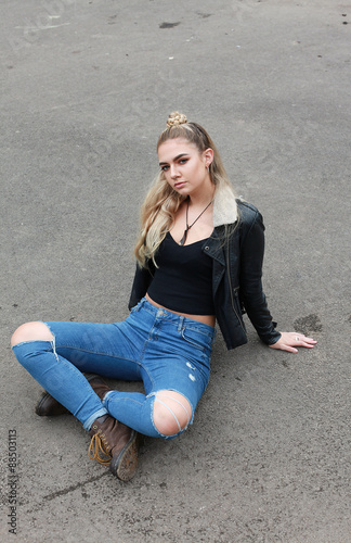 tough teenage girl sitting crossed legged on concrete