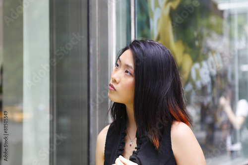 A young woman looking in a store window.