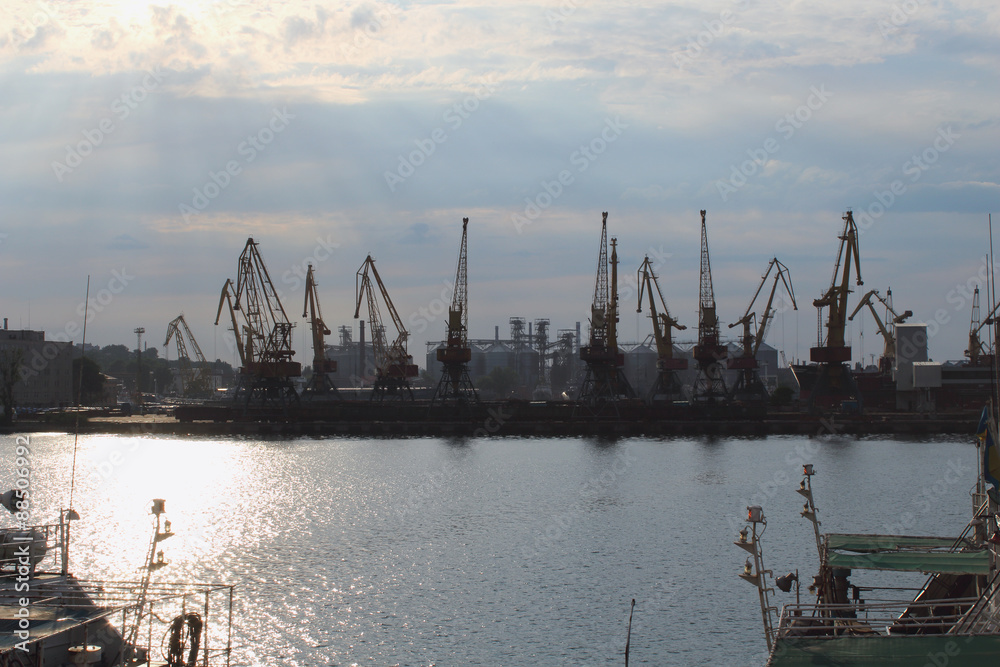 Silhouettes of big harbor cranes in the sea harbor with amazing sunlight