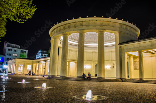 People are sitting in front of illuminated elisenbrunnen in german Aachen. photo
