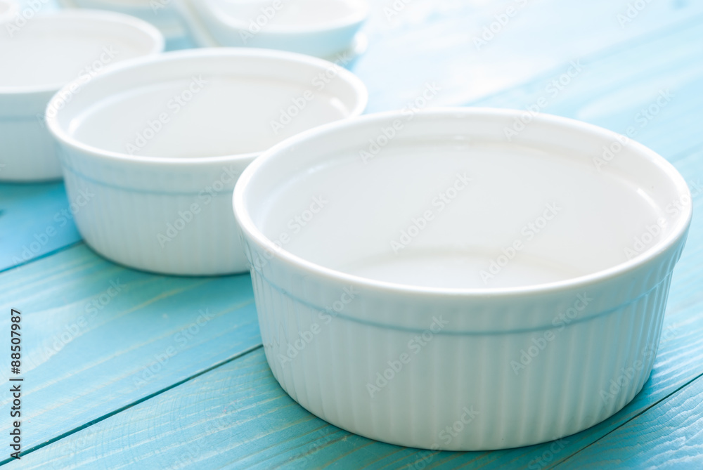 White Ramekin bowl on blue wooden board White Ramekin bowl on blue wooden board