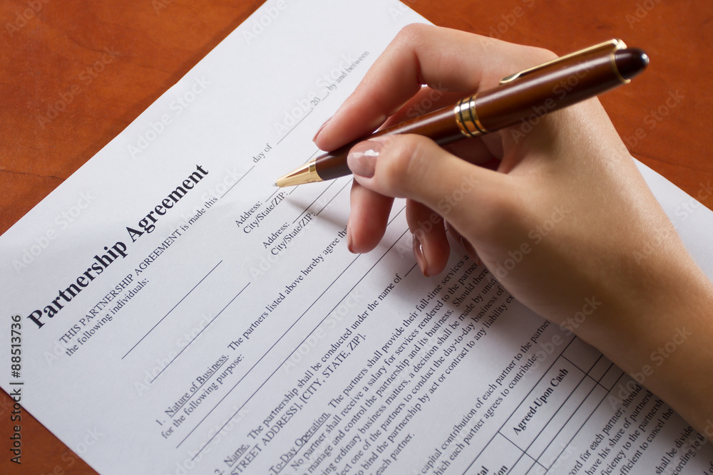 Female hand filling Partnership Agreement Female hand filling Partnership Agreement