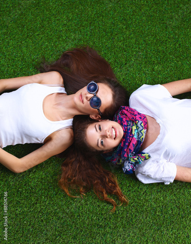 Two pretty girls lying on the fresh green grass 