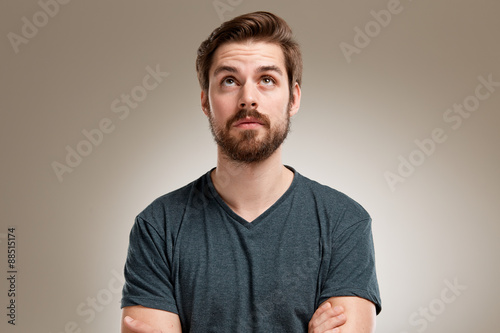 Portrait of young man with beard, looking up straight photo