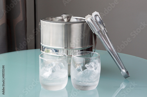 Glass of cold water and ice with stainless bucket