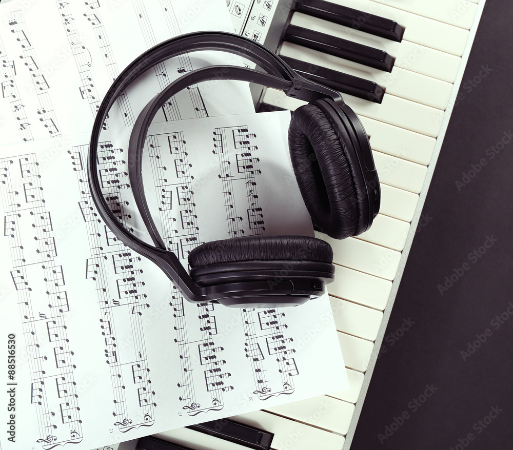 Headphones with music notes on synthesizer close up Headphones with music notes on synthesizer close up