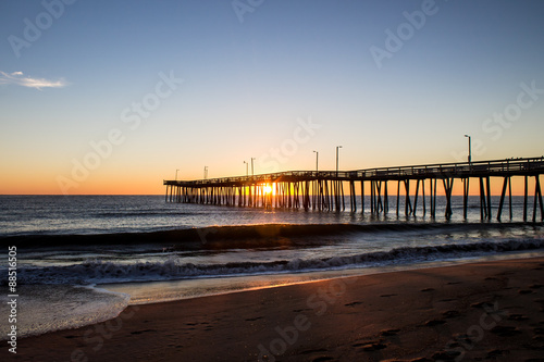 Virginia Beach fishing pier at sunrise as seen in silhouette.