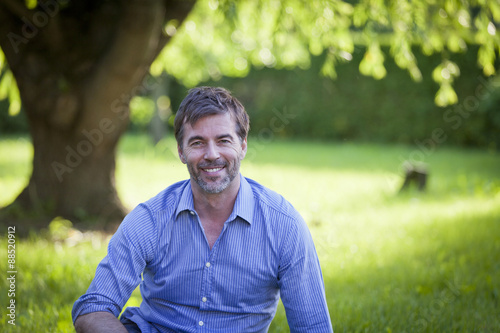 Portrait Of A Mature Man Smiling at the Camera sitting at the park