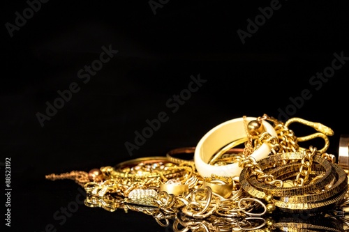 Bunch of gold jewelry against black background with copy space for text.