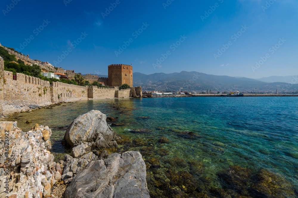 Red Tower (Kizil Kule) and the ruins of the fortress wall near the shore. The Mediterranean coast. Alanya. Turkey