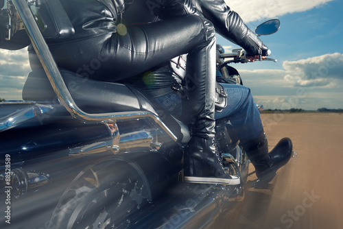 Biker Man and woman wearing black leather jackets riding on motorcycle