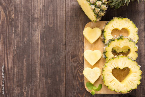 Pineapple slices with a cut in the shape of hearts on wooden bac