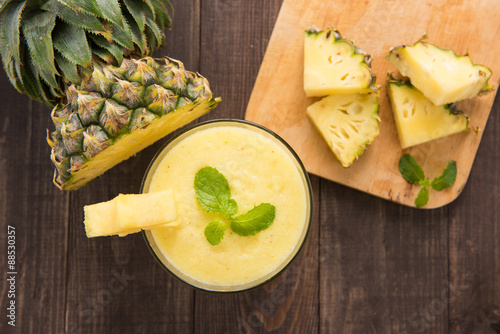 Pineapple smoothie with fresh pineapple on wooden table