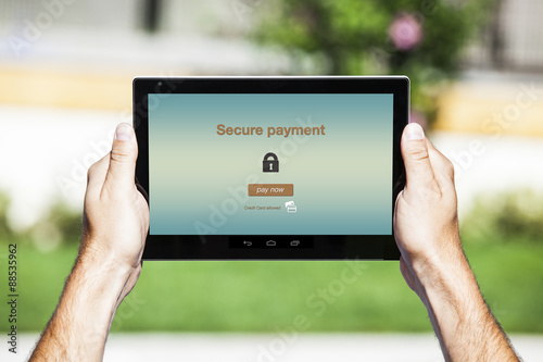 Hands holding tablet. Secure payment on the screen. Turquoise interface background.