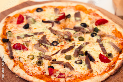 Pizza with meat, tomatoes and olives