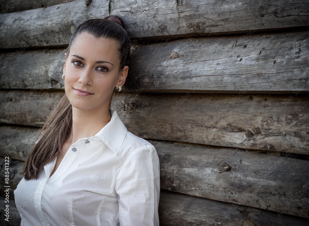 Seductive young woman enjoys at the park. Wooden background. Looking at camera. Horizontal orientation. Seductive young woman enjoys at the park. Wooden background. Looking at camera. Horizontal orientation.