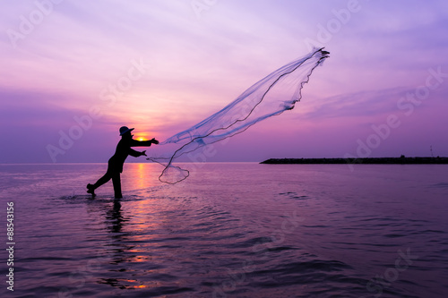 Fisherman throwing net at sunset.