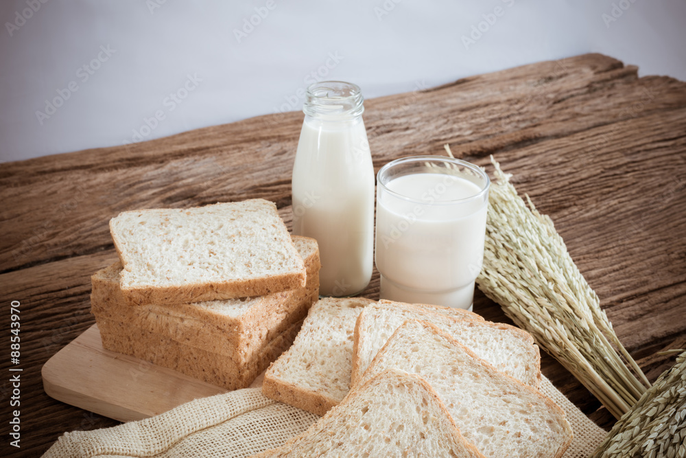 glass of milk and whole wheat bread on the wooden board glass of milk and whole wheat bread on the wooden board