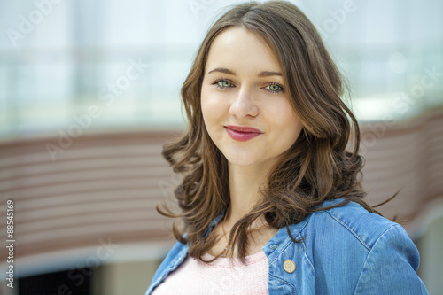 Happy brunette woman in blue jeans jacket, against summer street Free Download Happy brunette woman in blue jeans jacket, against summer street - GFXLoad
